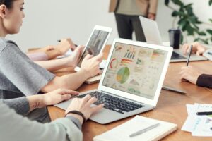 Coworkers analyzing data charts on laptops during a team meeting.