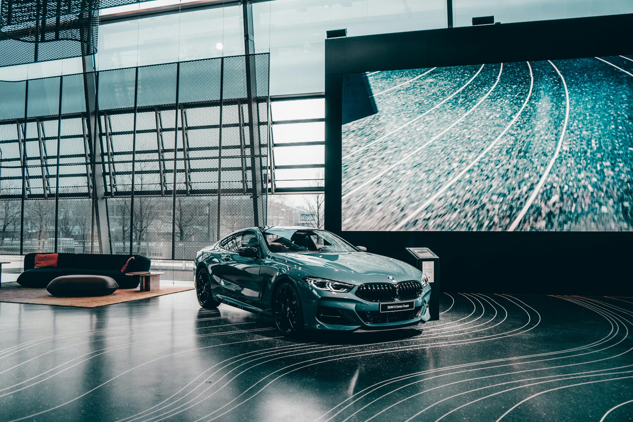 Elegant luxury coupe showcased in a modern Munich auto showroom with glass architecture.