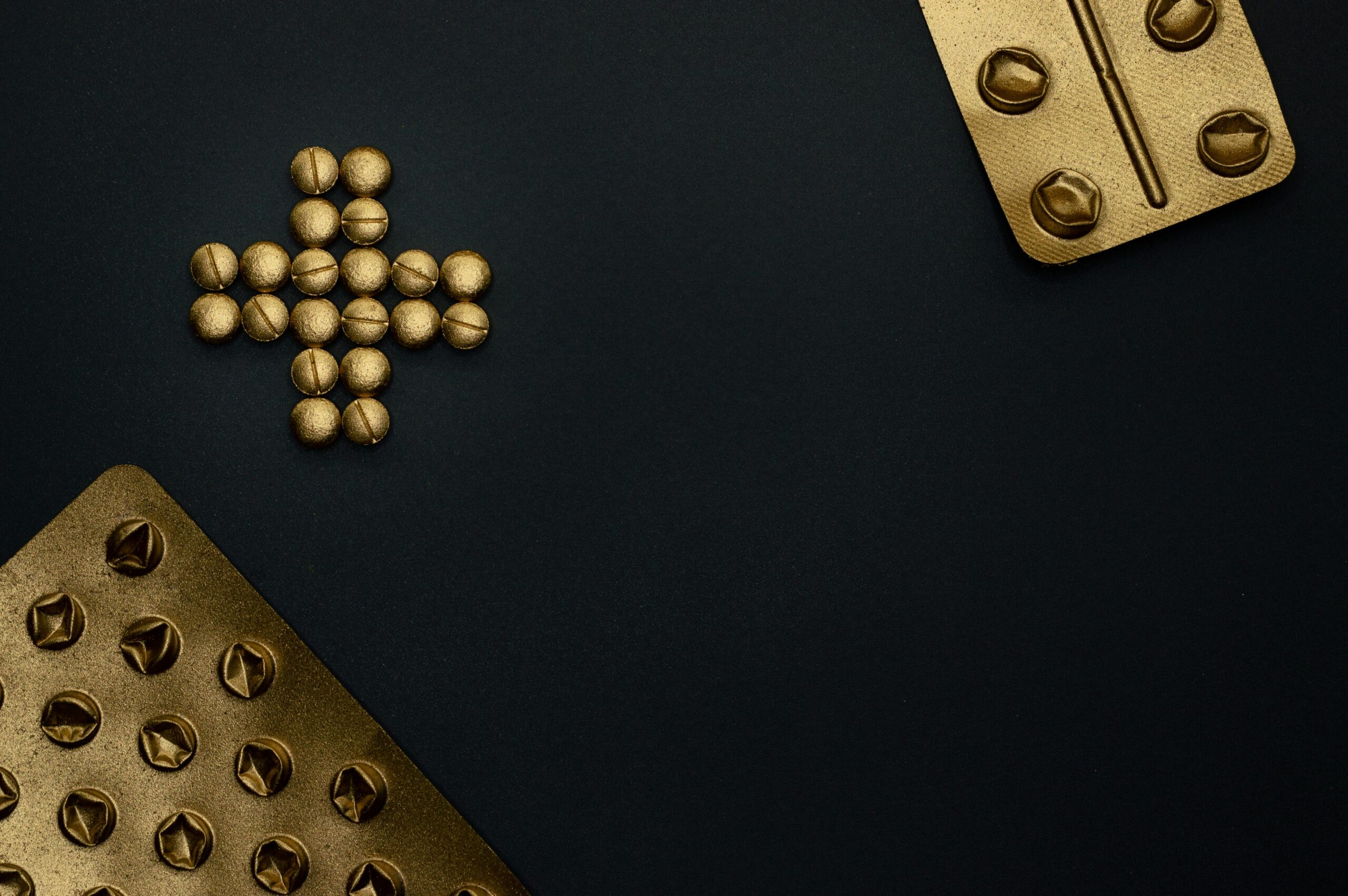 Gold tablets and blister packs on a black background. Conceptual healthcare image with copy space.